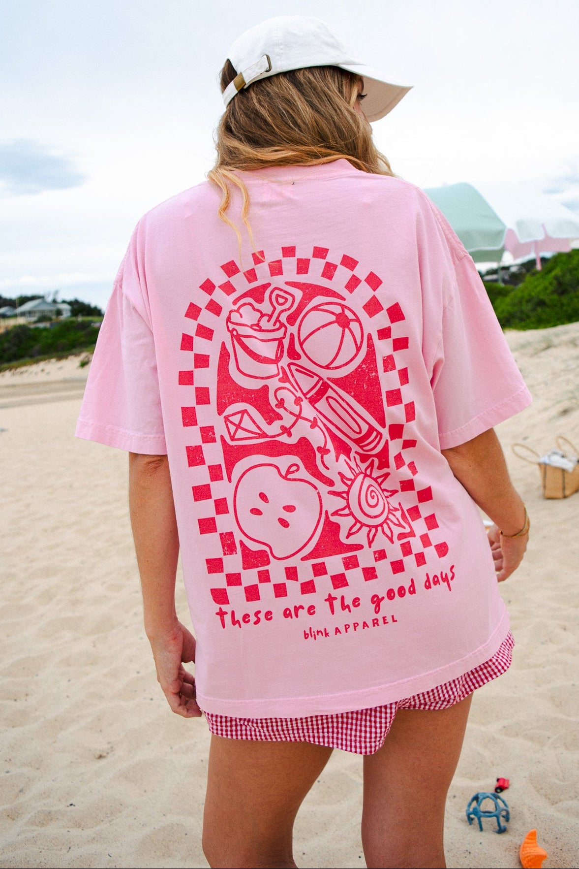 Person wearing a pink t-shirt with a graphic design on a beach